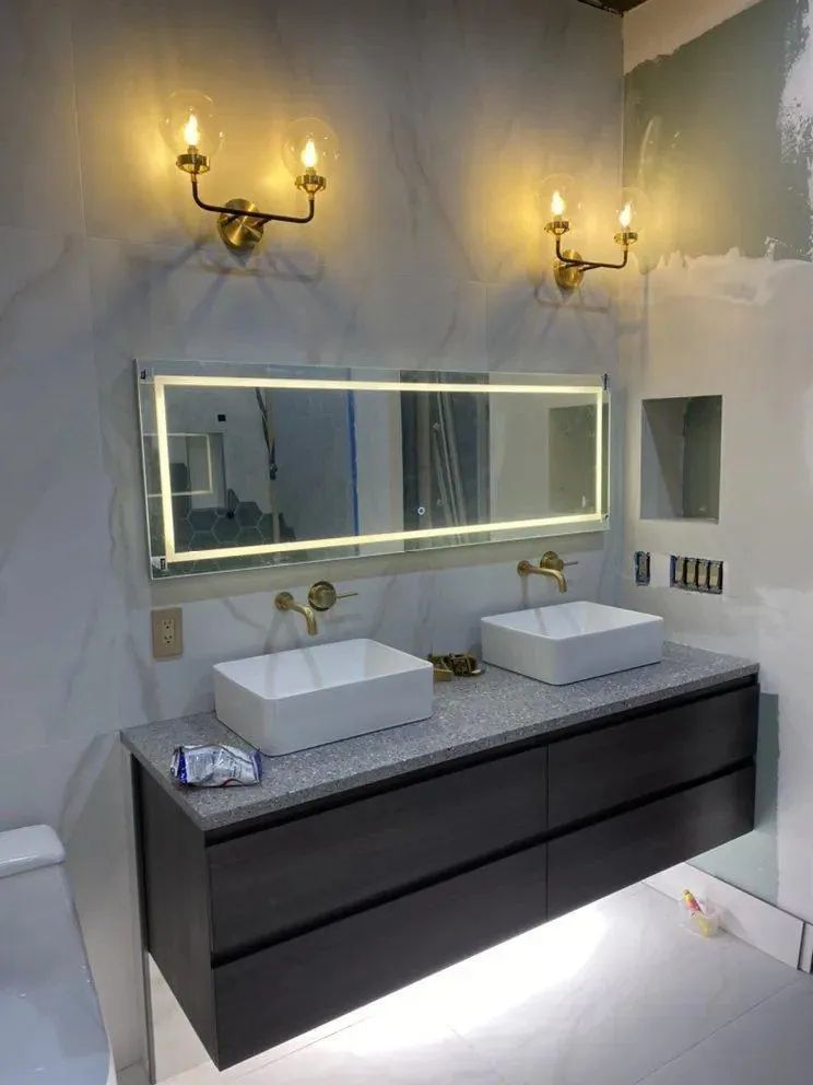 Modern bathroom vanity with double vessel sinks, illuminated mirror, and wall sconces