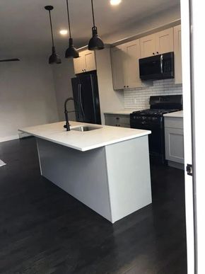 Modern kitchen with white island, black appliances, and pendant lights
