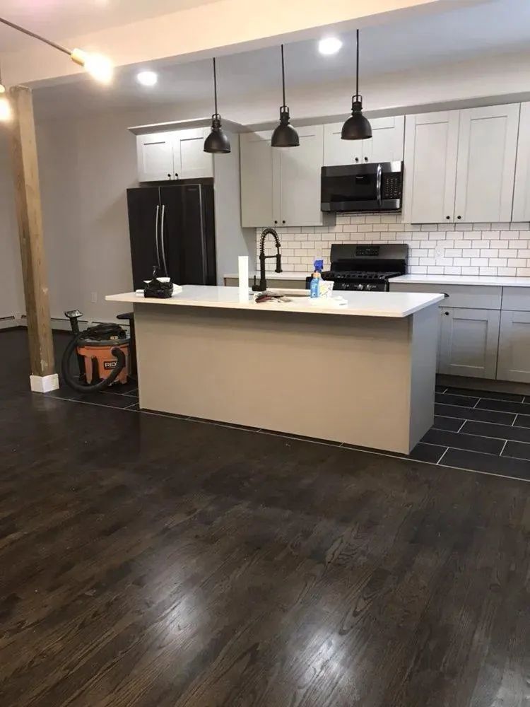 Modern kitchen with white cabinets, black appliances, island, and dark wood floors