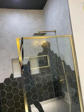 Modern staircase with black and white hex tile walls and a gold-framed glass railing.