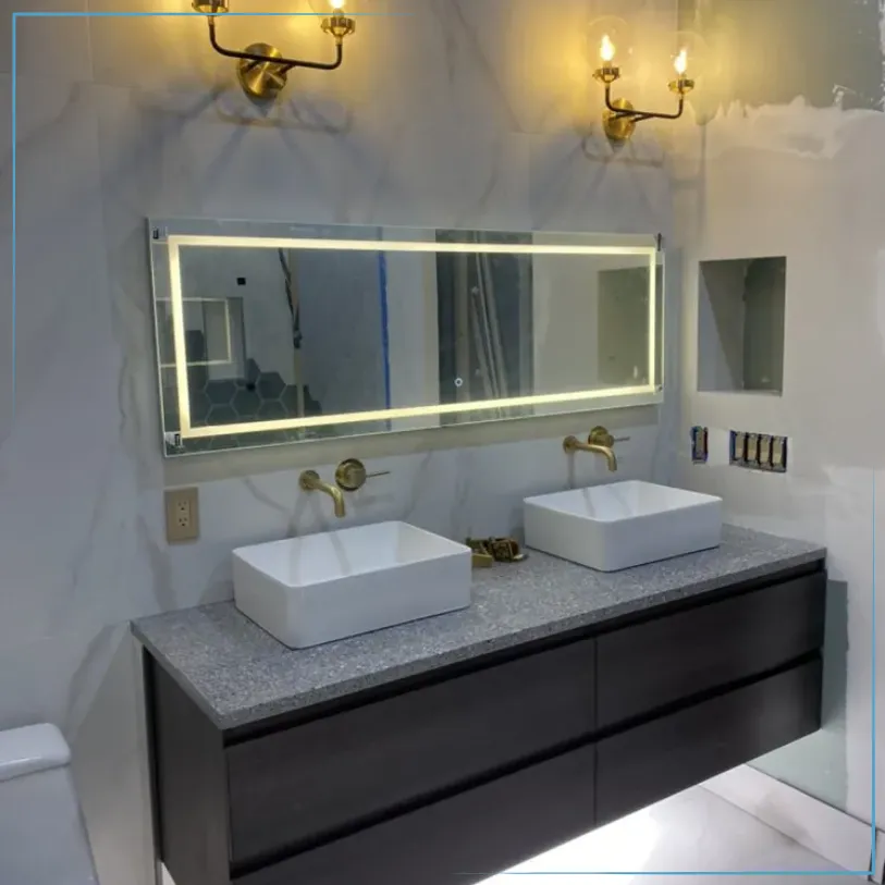 Modern bathroom vanity with double sinks, backlit mirror, marble walls, and brass sconces
