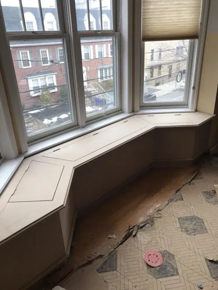 Window seat bench overlooking a snowy street, with beige trim and carpeted floor.