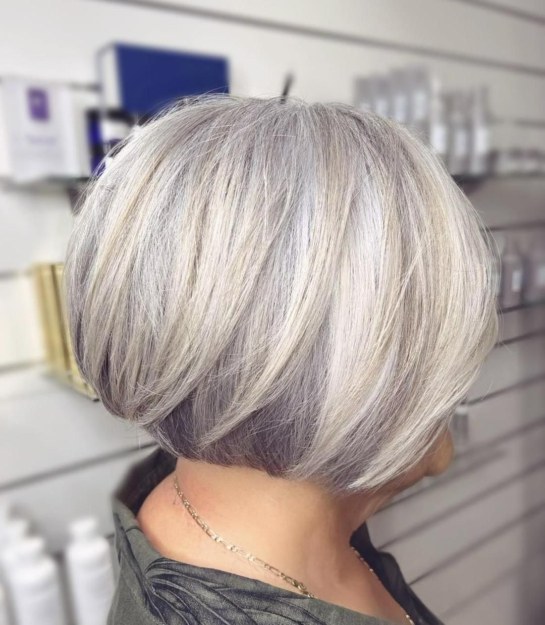A Woman With Short Gray Hair is Standing in Front of a Wall — Strut Hair & Beauty In Maroochydore, QLD