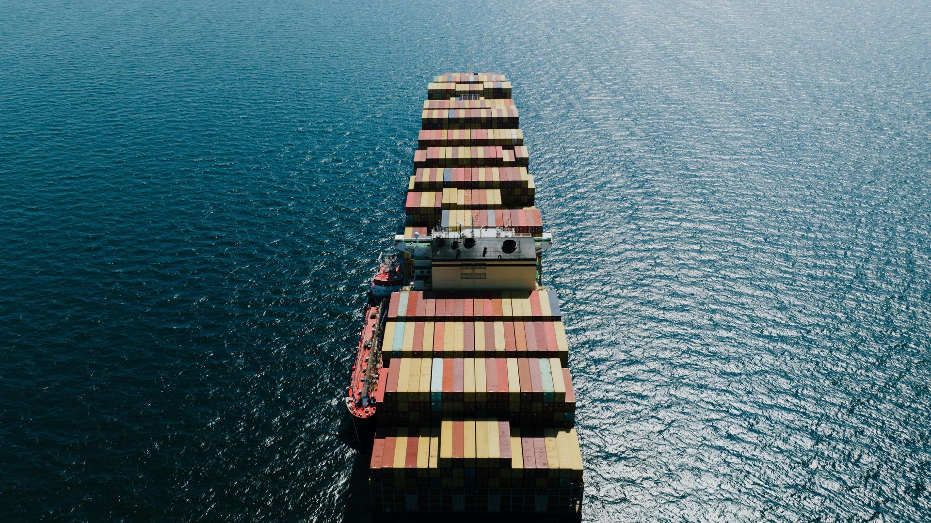 Uma vista aérea de um grande navio porta-contêineres flutuando sobre um corpo d'água.