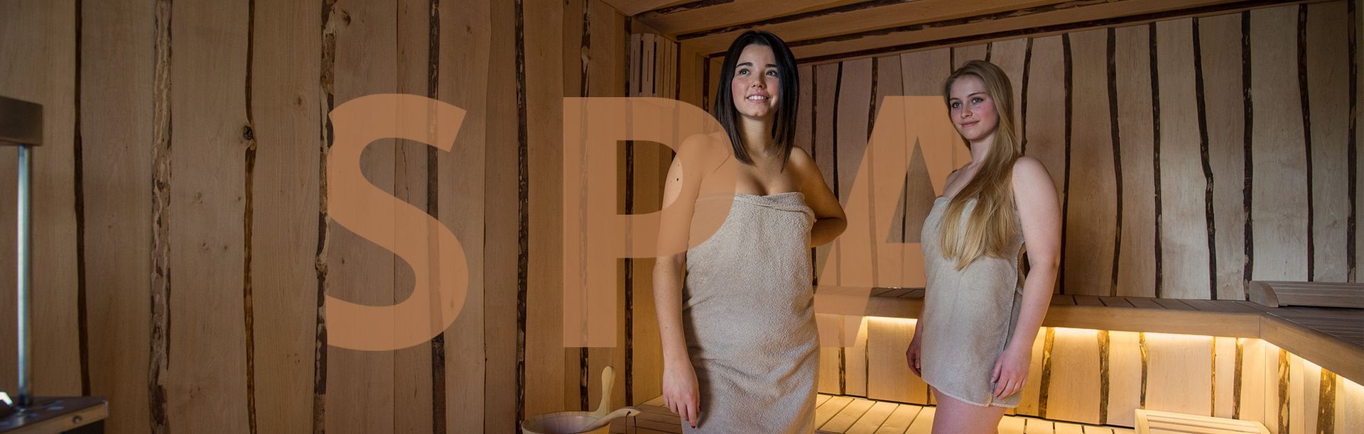Due donne sono in una sauna in legno.