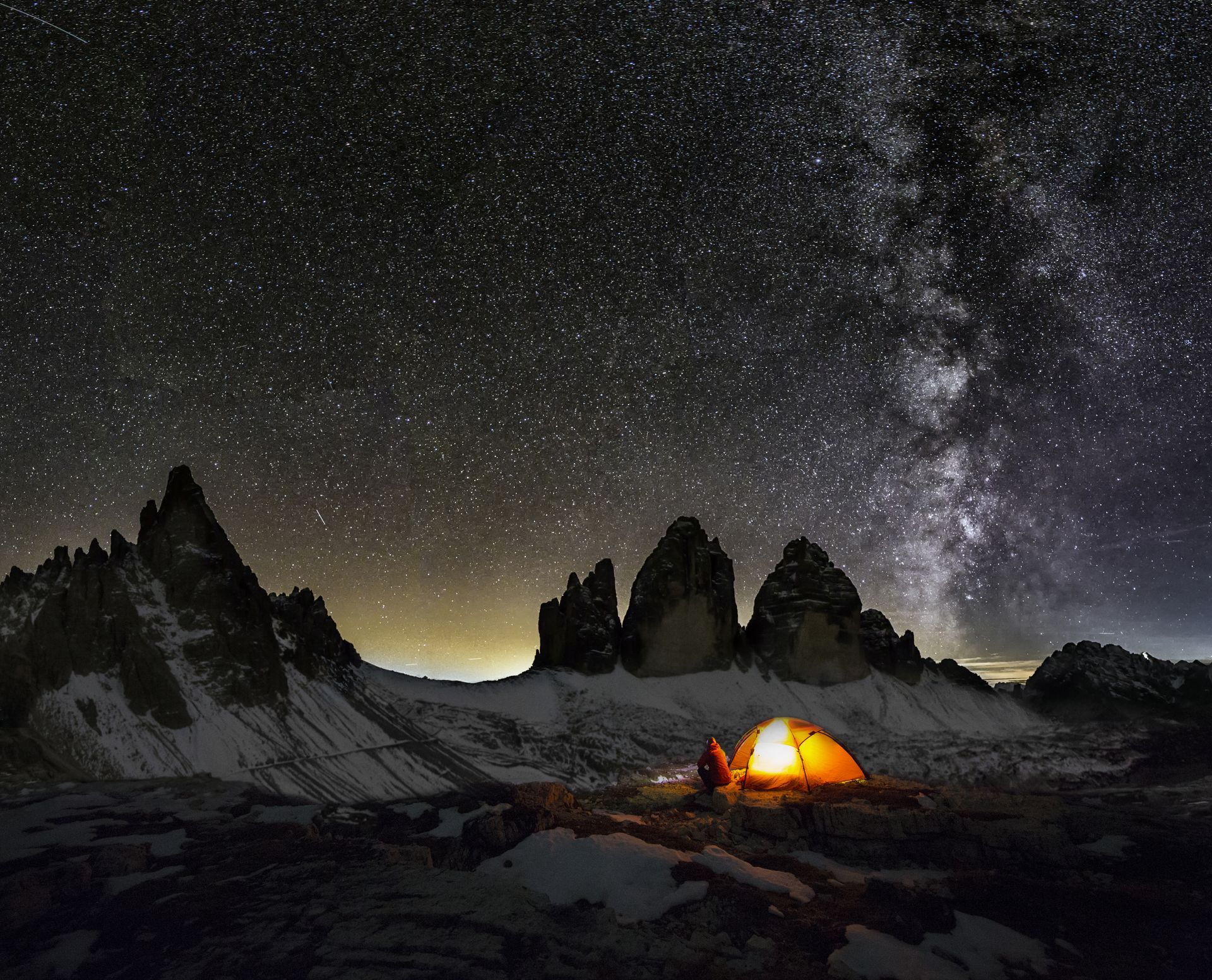 Una tenda è illuminata sotto un cielo notturno stellato