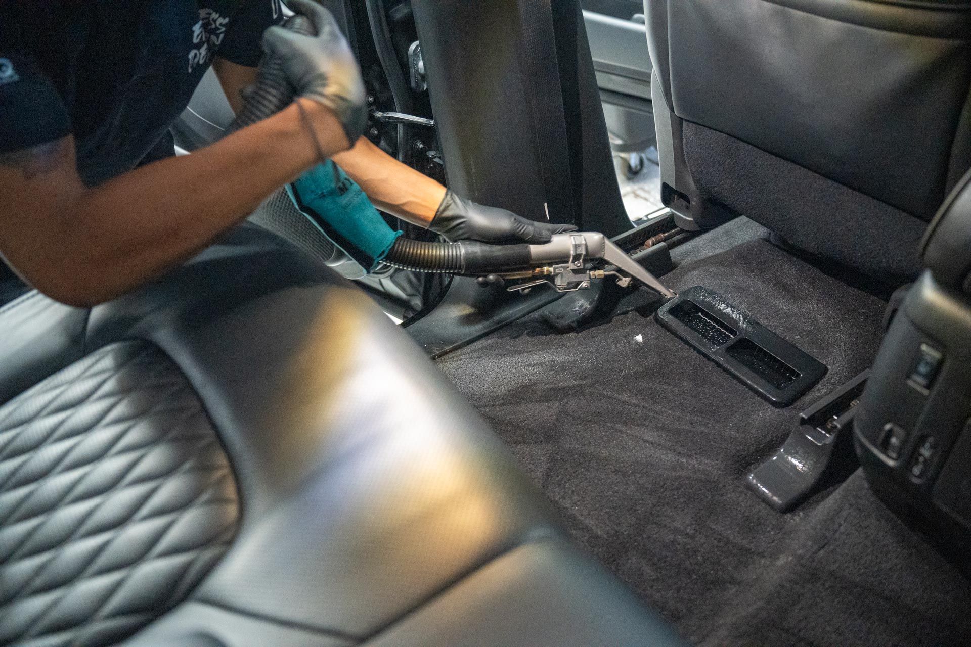 A person wearing blue gloves is polishing the hood of a white car.