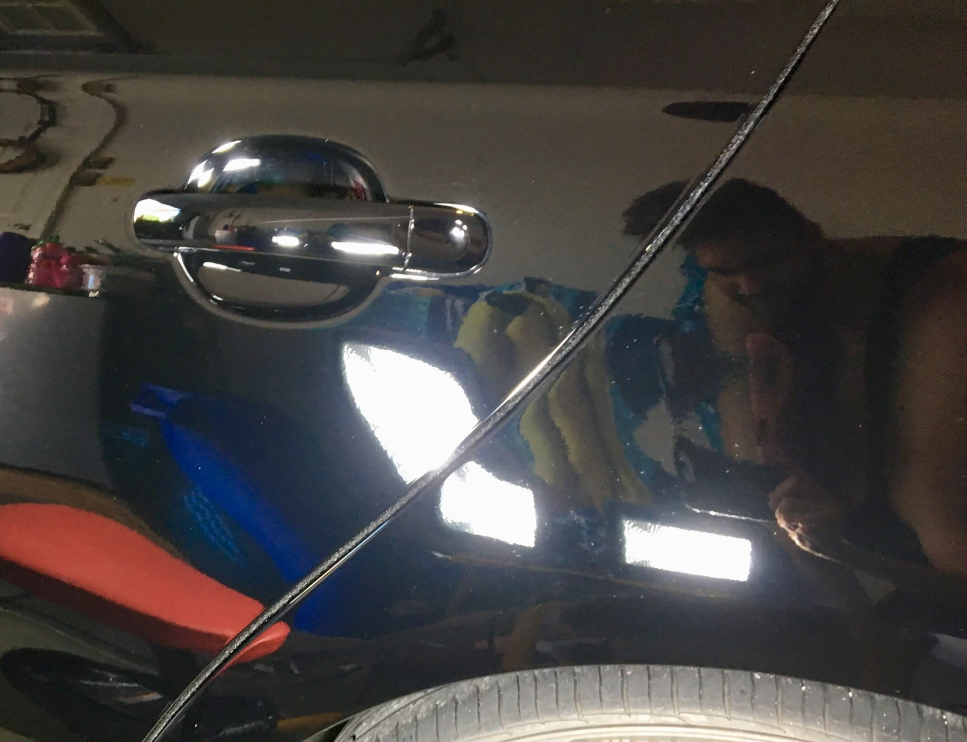 A close up of a car door handle with a reflection of a person