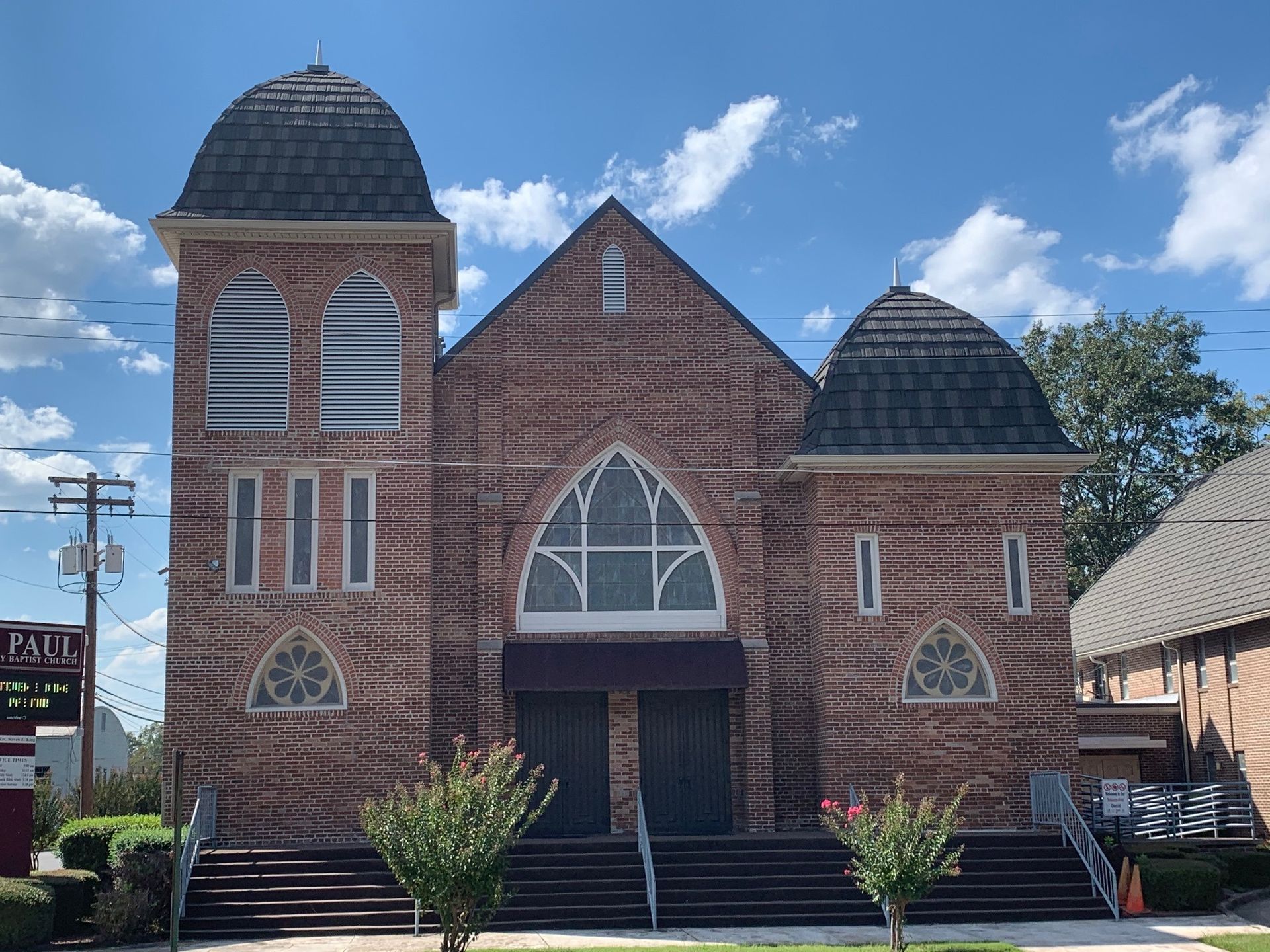 Brick church with twin domed towers and arched windows under a bright blue sky