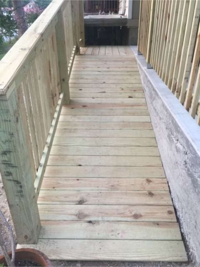 Narrow wooden accessibility ramp with handrails leading down to a lower level