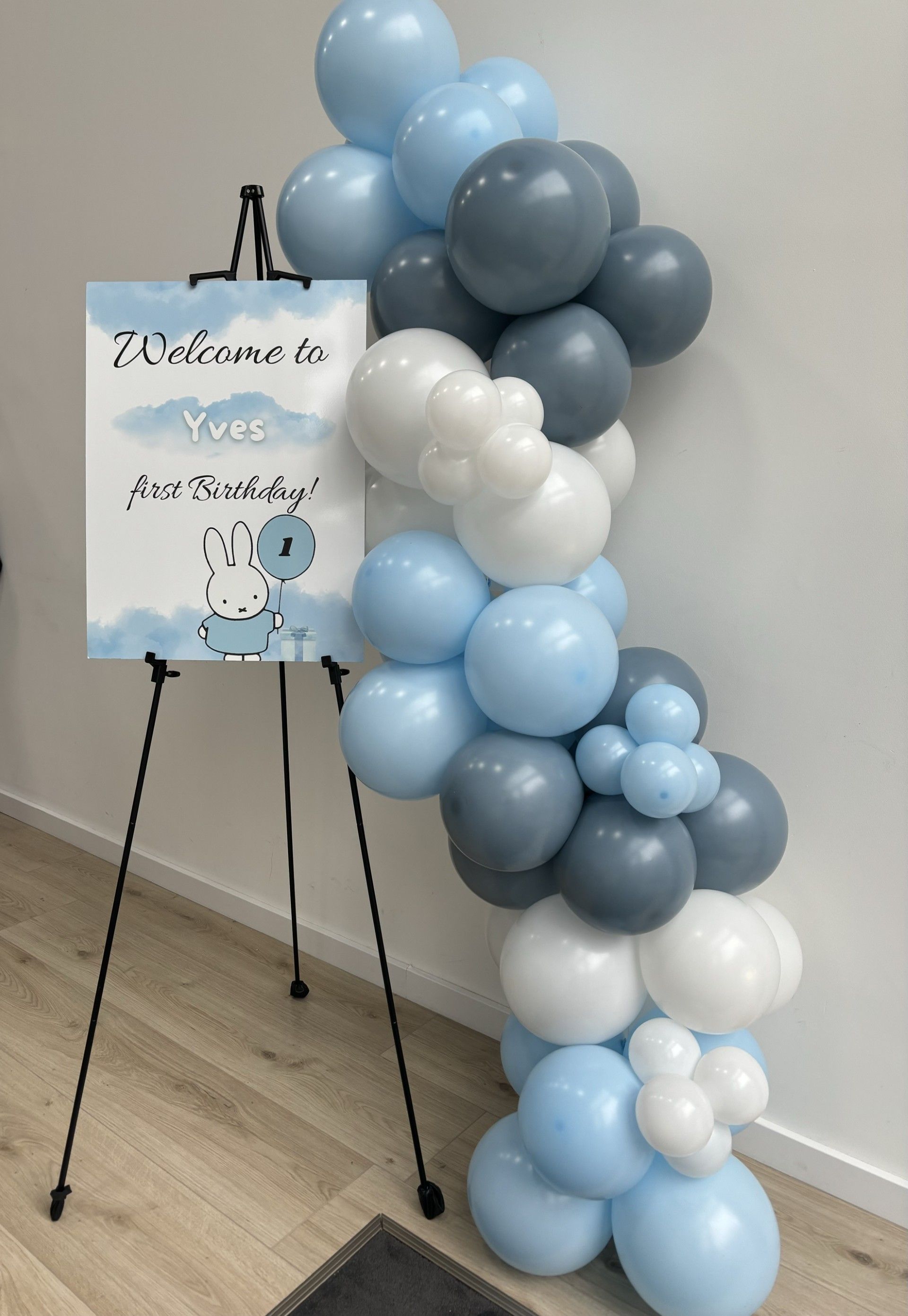 Een welkomstbord is omgeven door blauwe en witte ballonnen