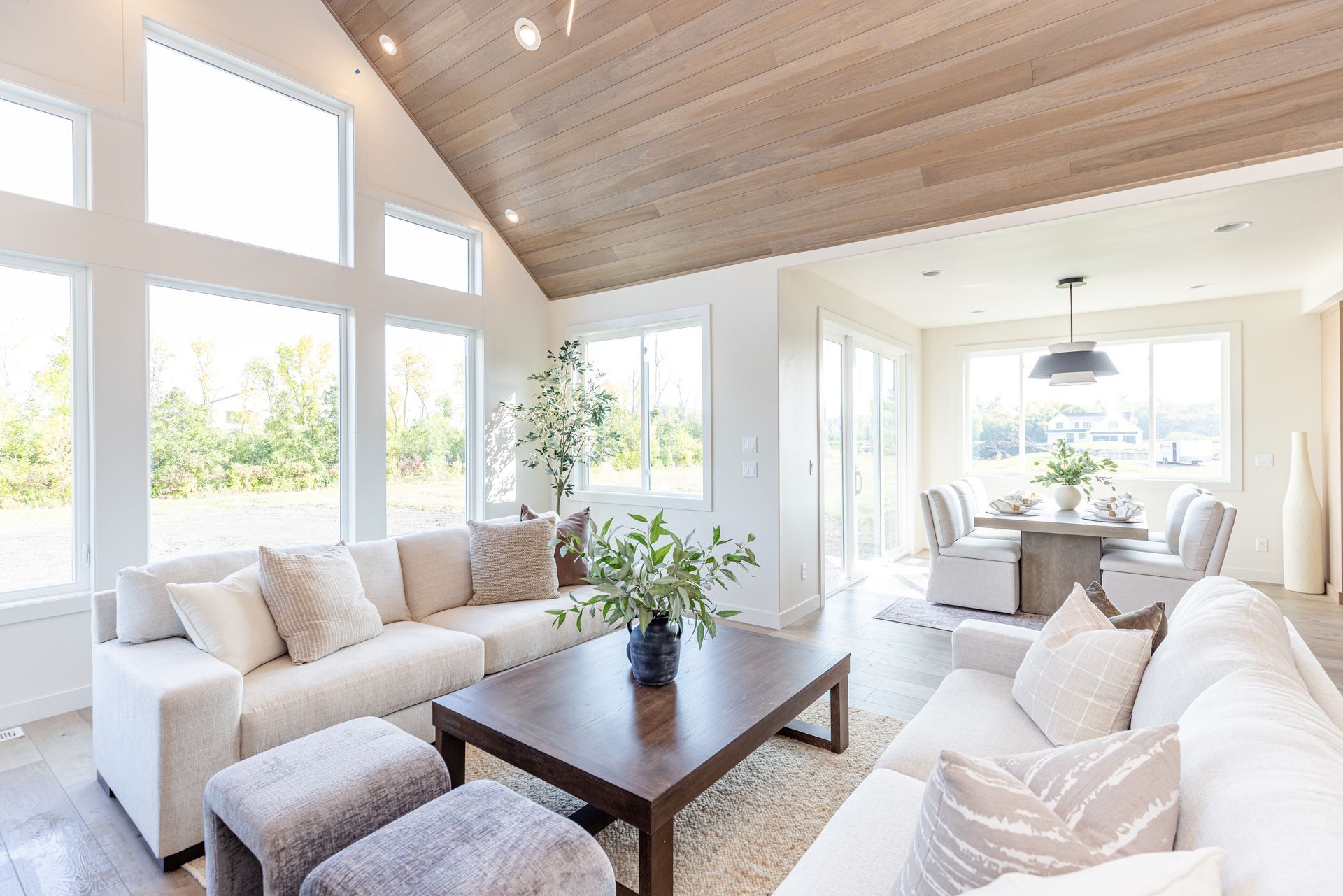Bright, sunlit living room with white sofas, wooden coffee table, and vaulted ceiling