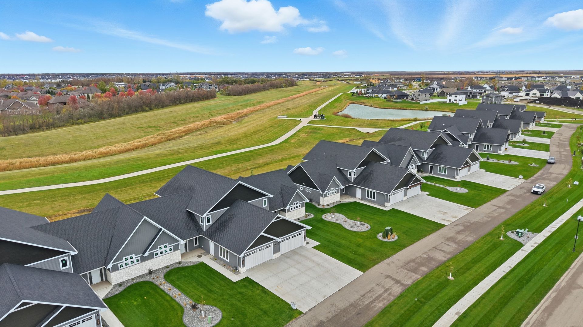 Aerial view of a suburban neighborhood with rows of gray-roofed houses and green lawns along a curving road