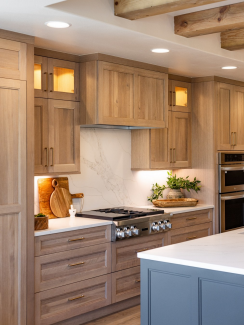 Warm cabinetry, softly veined surfaces and brass-toned hardware give the kitchen a furniture-like quality. 