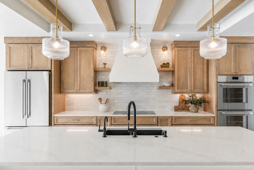Bright modern kitchen with white island, wood cabinets, black faucet, and pendant lights