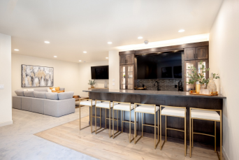 The bar remains connected to the adjoining lounge, giving the lower level a natural gathering point. 