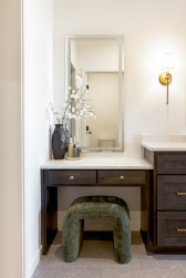 Dark-stained cabinetry, warm brass, and a dedicated makeup vanity give the suite a personal, polished character.