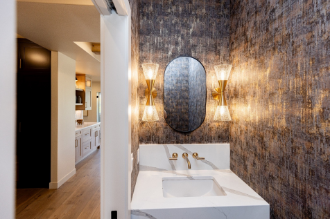 Textured wallcovering and sculptural brass lighting give the powder bath a dramatic identity. 