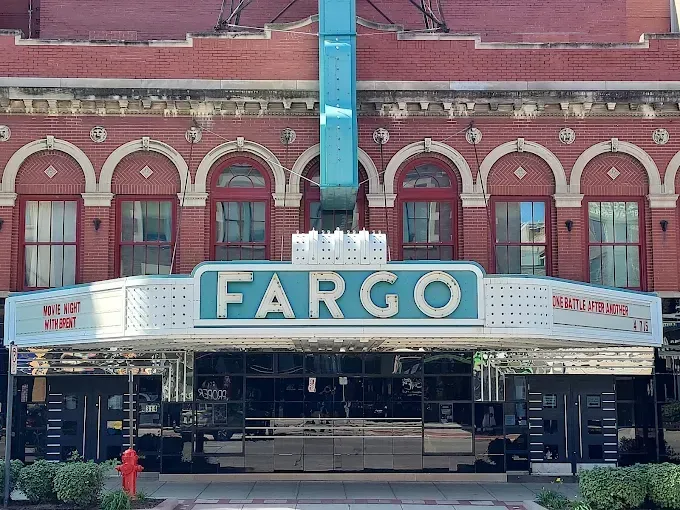 Fargo Theatre The historic Fargo Theatre features a red brick facade with arched windows and a large teal, illuminated marquee sign.
