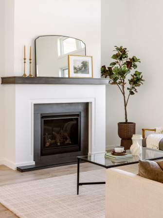 The tailored fireplace pairs a dark inset with a warm stained mantel. 
