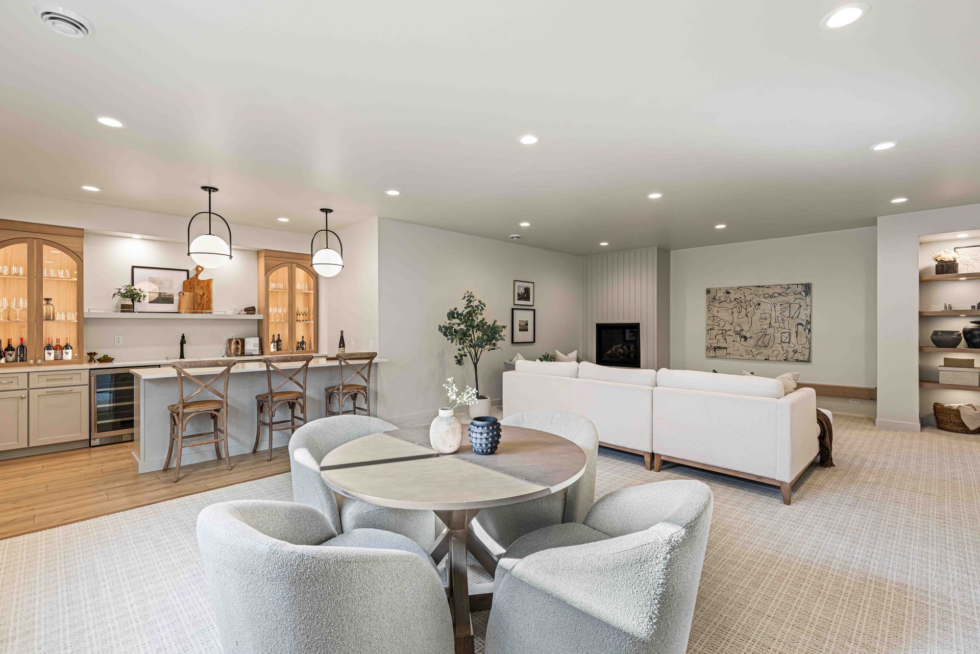 Bright open-concept living room with white sofas, round coffee table, and kitchen island with bar stools