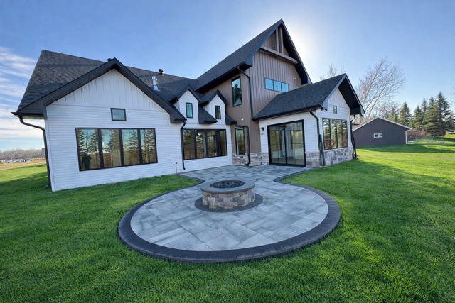 Modern home with a gray stone patio and fire pit in the backyard.