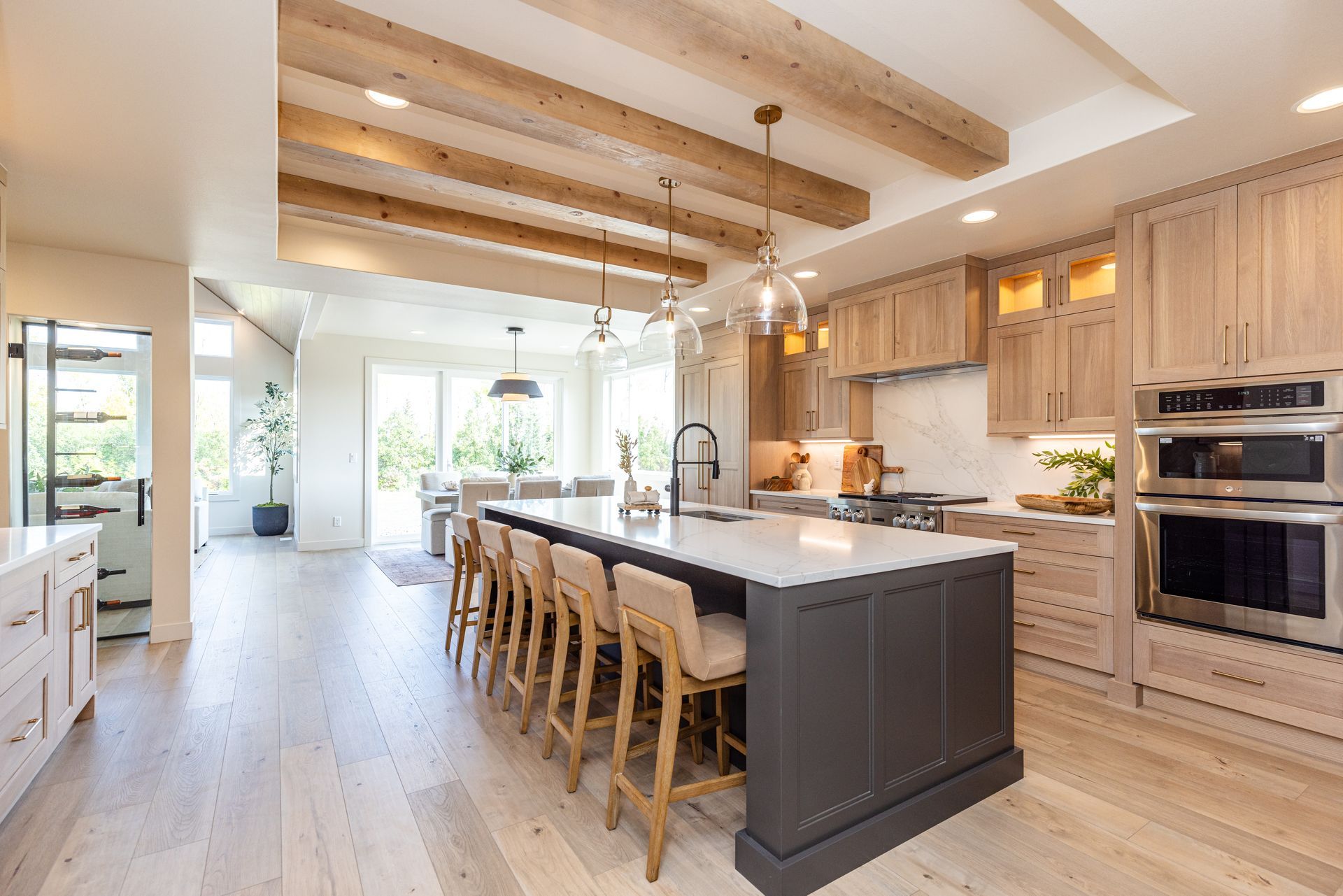 Bright modern kitchen with wood cabinets, large island, bar stools, and exposed ceiling beams