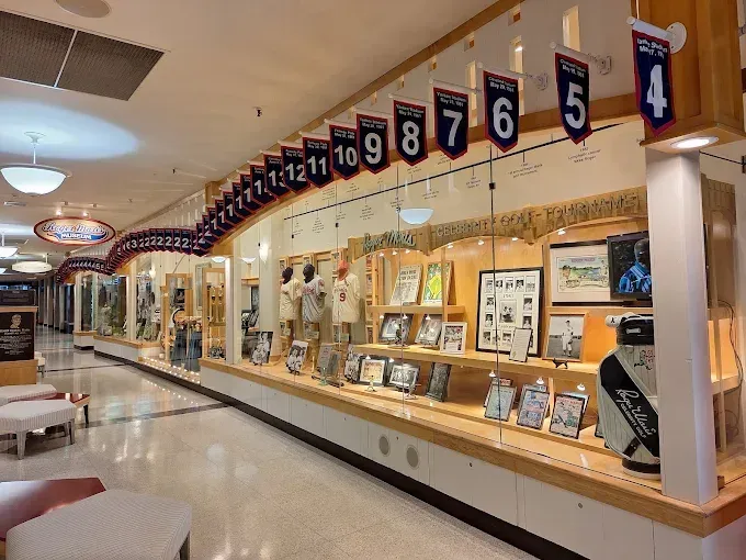 Roger Maris Museum A display case in a corridor featuring numbered pennants, framed photos, and memorabilia from a university sports team.