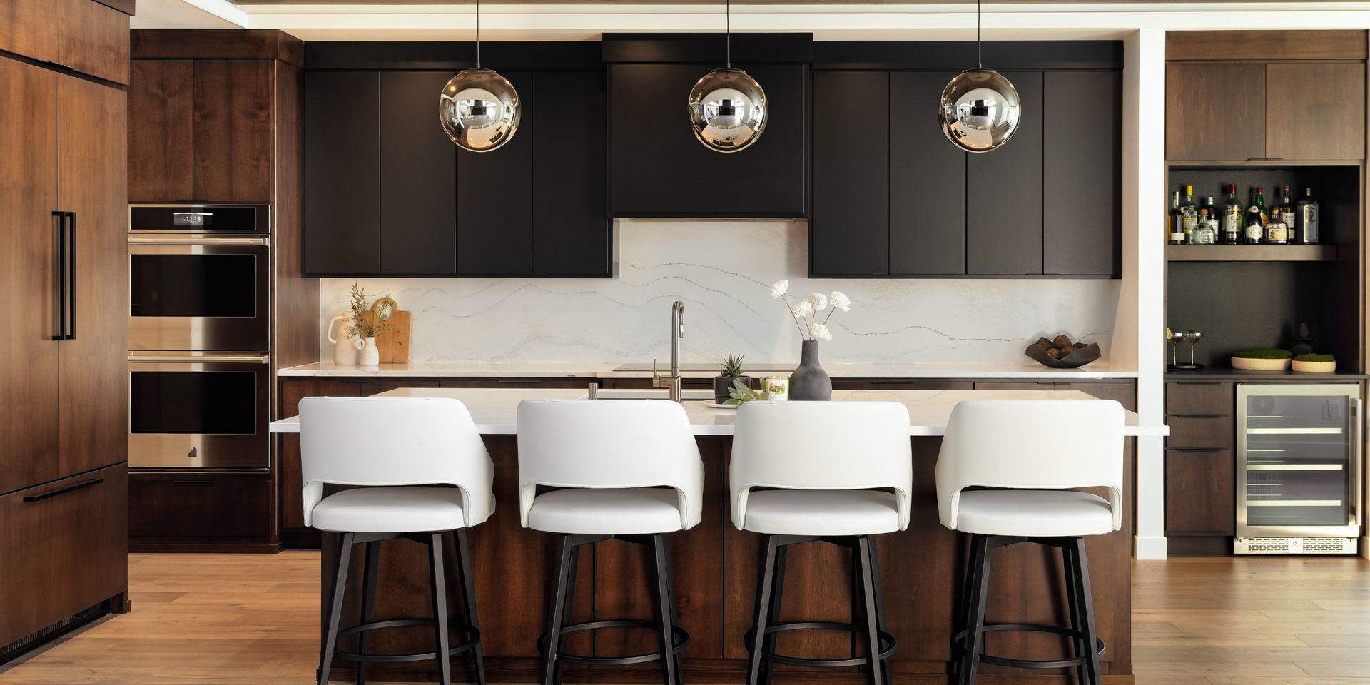 Modern kitchen with dark cabinets, island seating, pendant lights, and built-in appliances.
