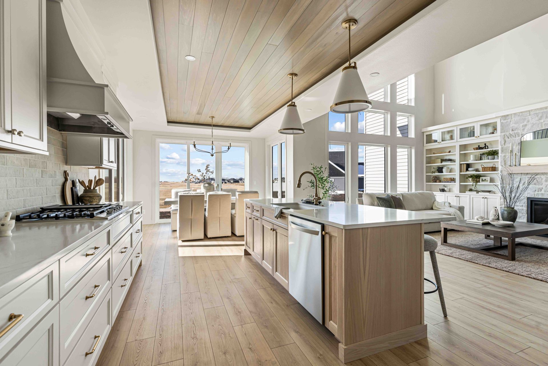 Bright modern kitchen with white cabinets, wood island, and vaulted ceiling with large windows