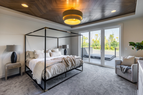 A wood-lined tray ceiling and broad doors to the outdoors create a quieter primary retreat. 