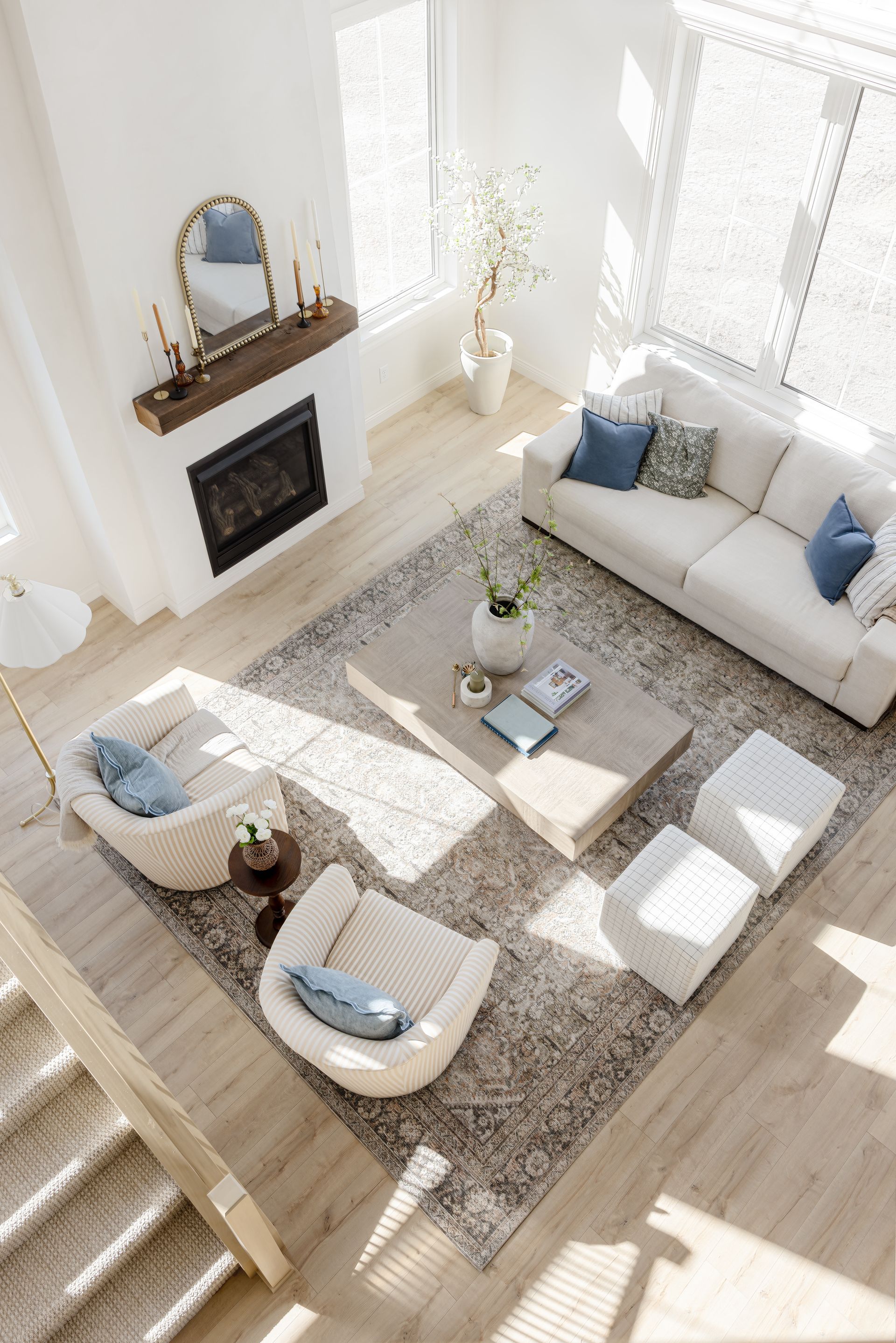 Living room with a stone fireplace, built-in shelves, light-colored sofas, and wood-beam ceiling.