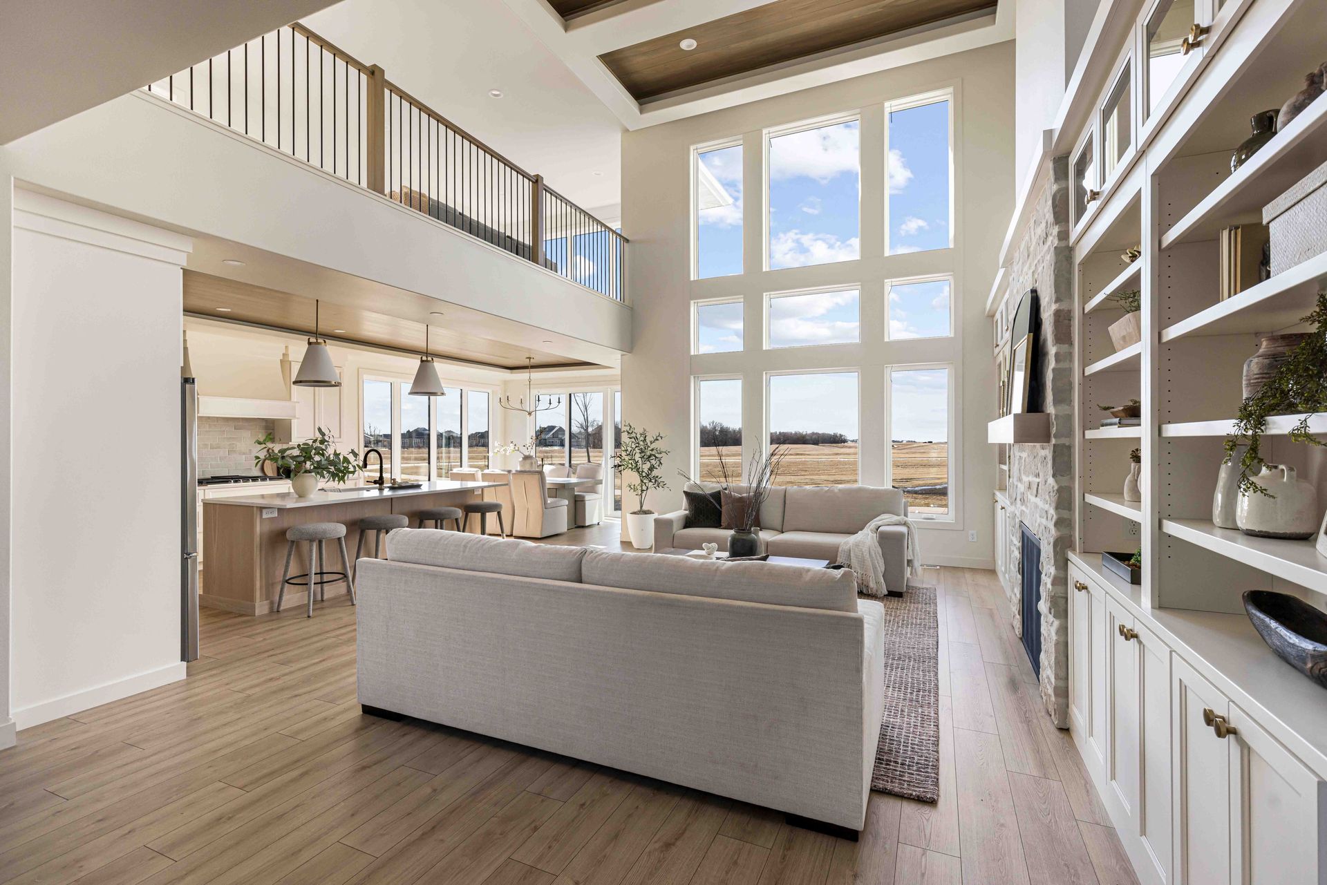 Spacious living area with fireplace, large windows, and open kitchen with wooden cabinets.