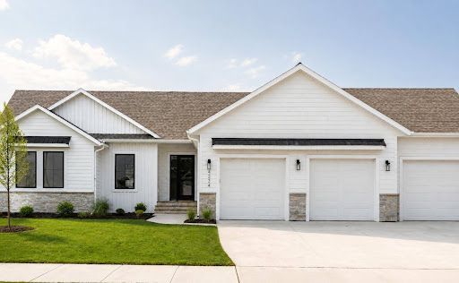 Single-story white suburban house with gray roof, two garage doors, and a green lawn.