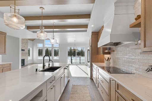 Bright modern kitchen with white island, pendant lights, and large windows overlooking a patio