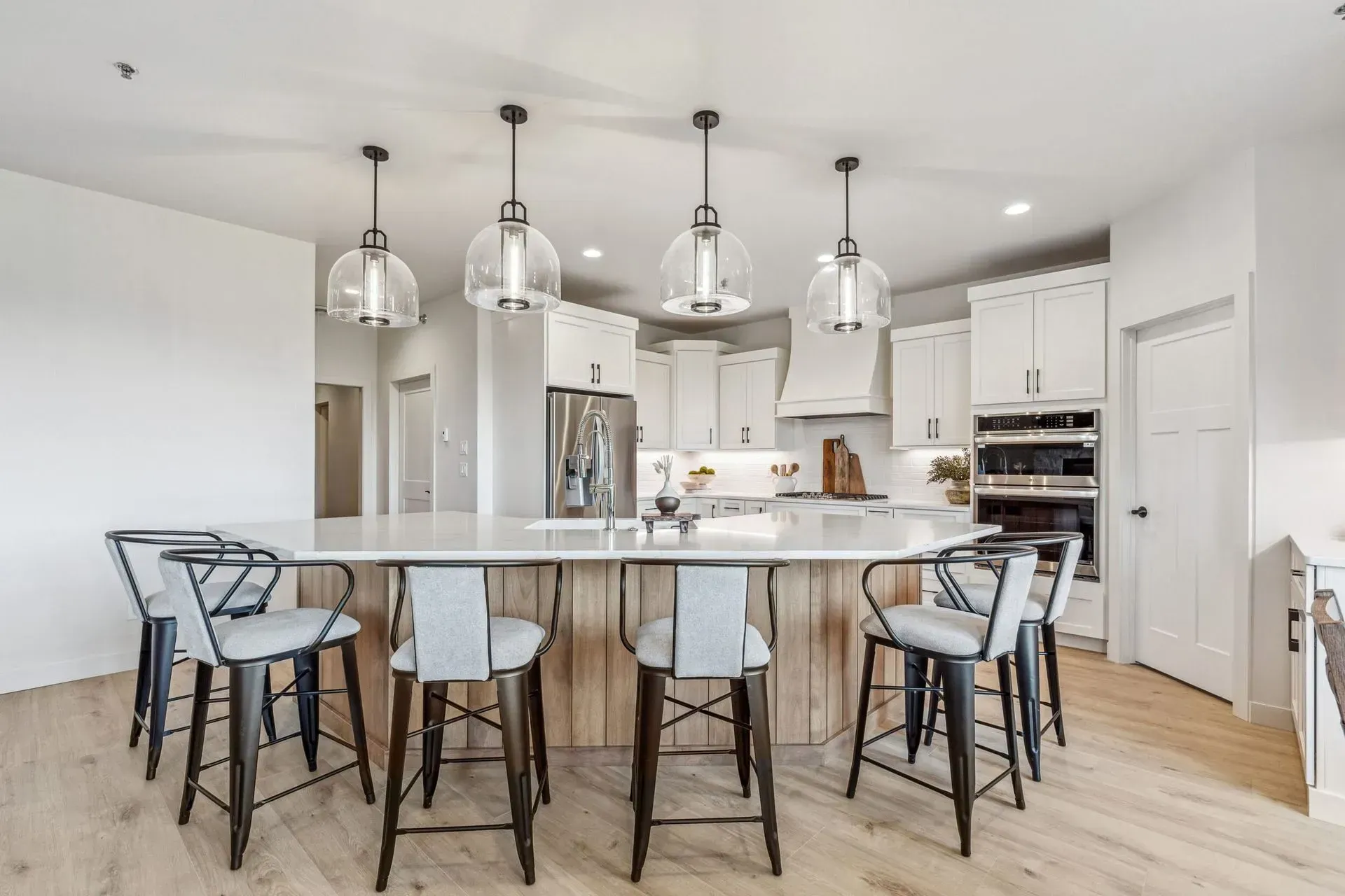 Bright modern kitchen with a large island, bar stools, pendant lights, and light wood floors
