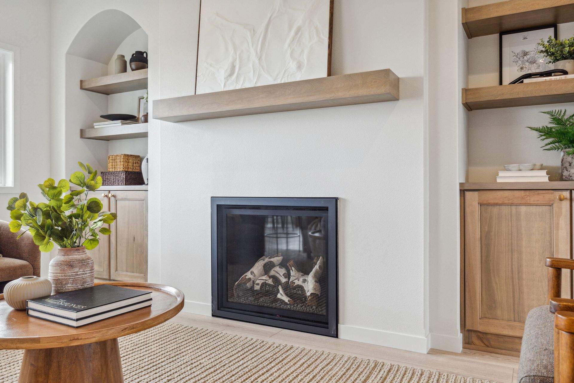 Modern living room with a fireplace, built-in shelving, and light wood accents