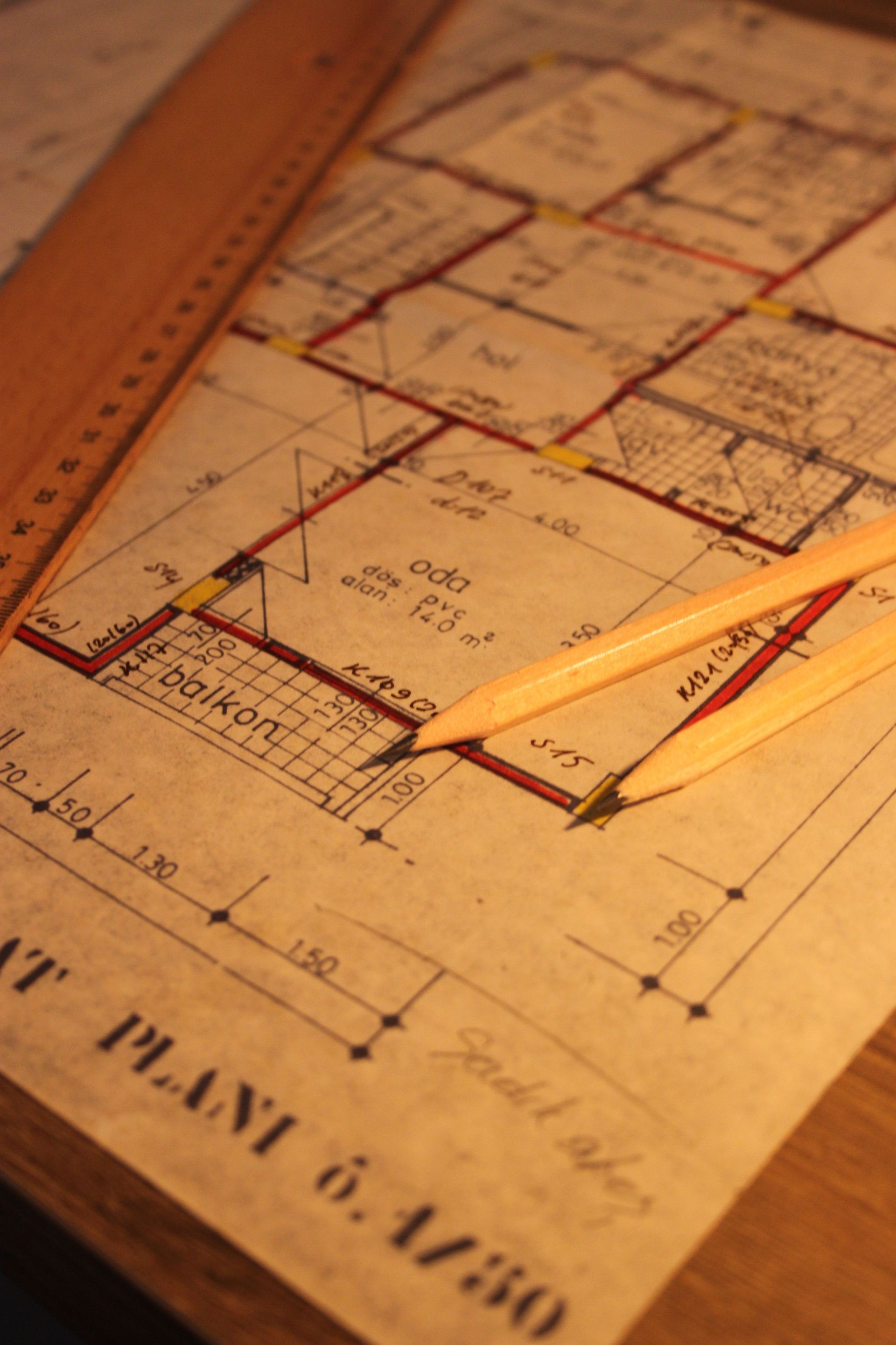 Architectural blueprint with a yellow pencil laid across it on a wooden surface