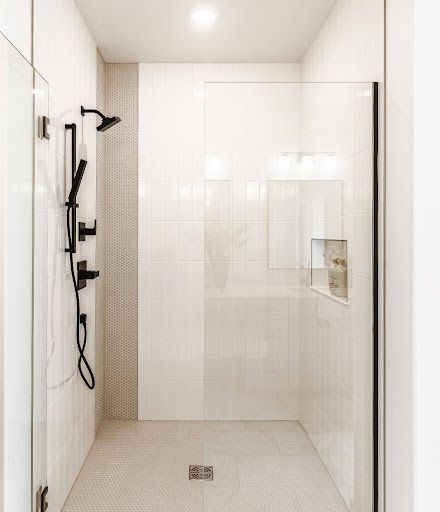 The walk-in shower pairs glossy white vertical tile with a fine penny-round accent and matching mosaic floor.
