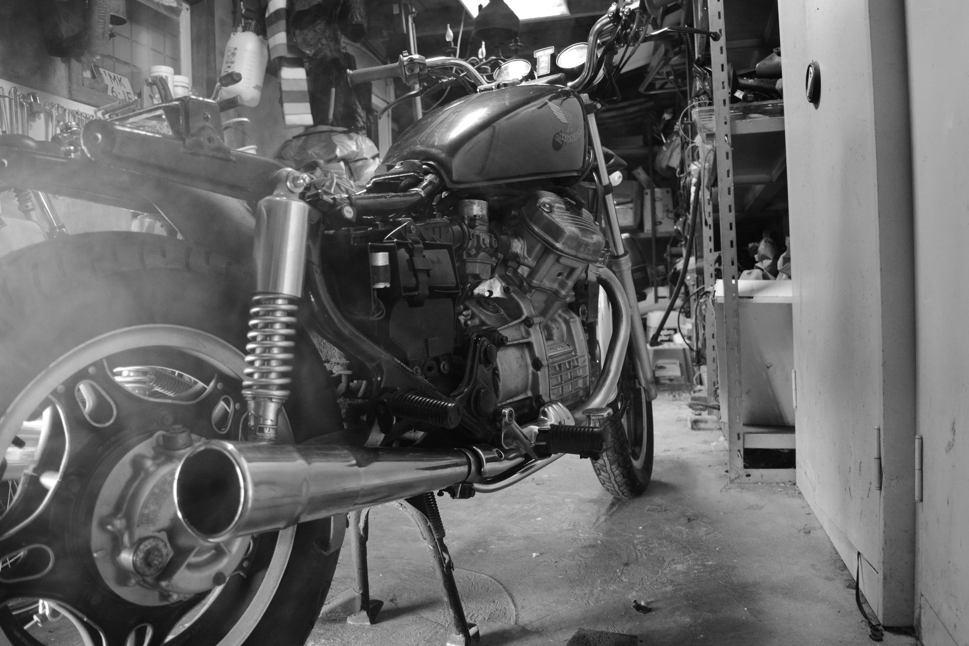 A black and white photo of a motorcycle in a garage.