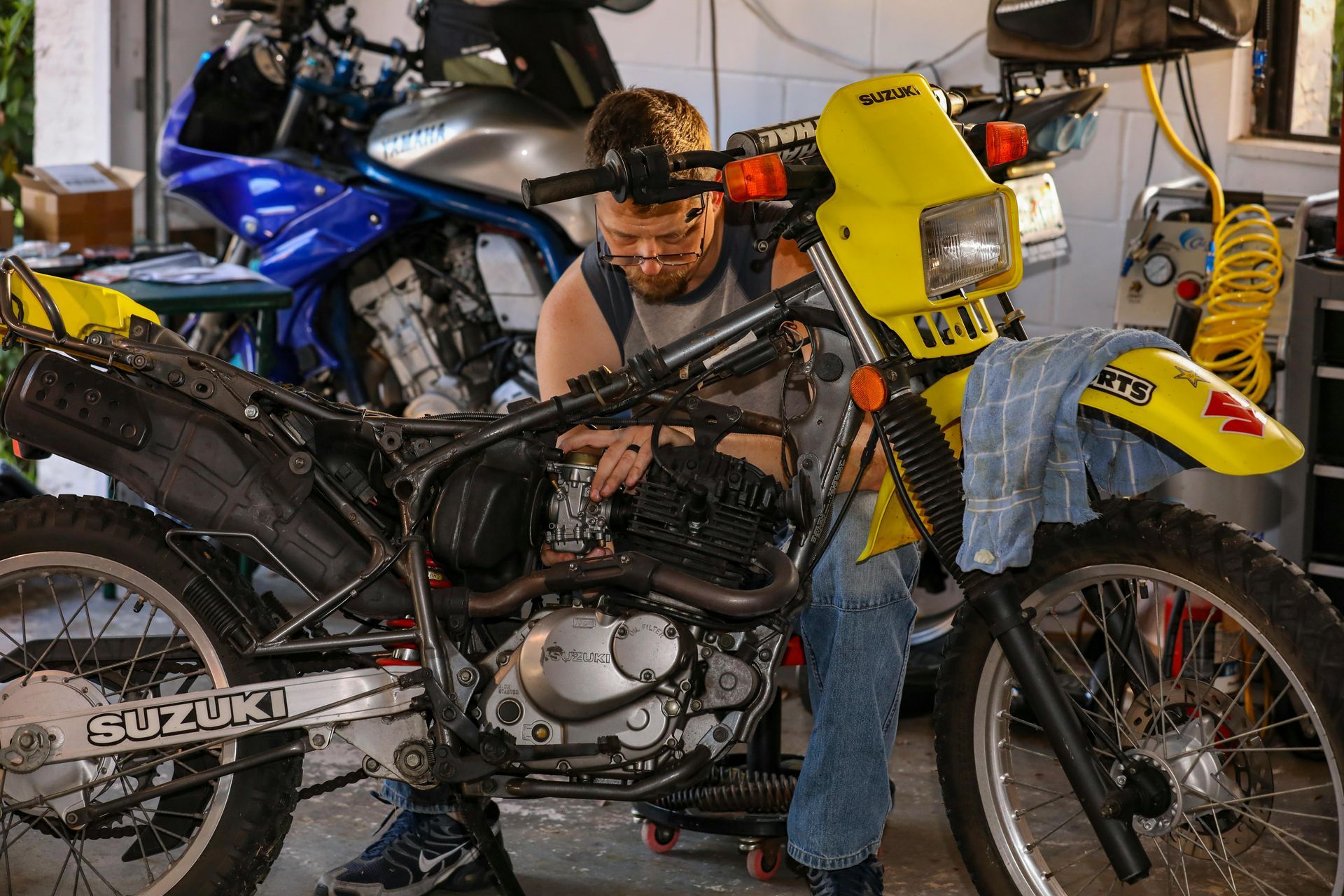 A man working on a suzuki motorcycle in a garage
