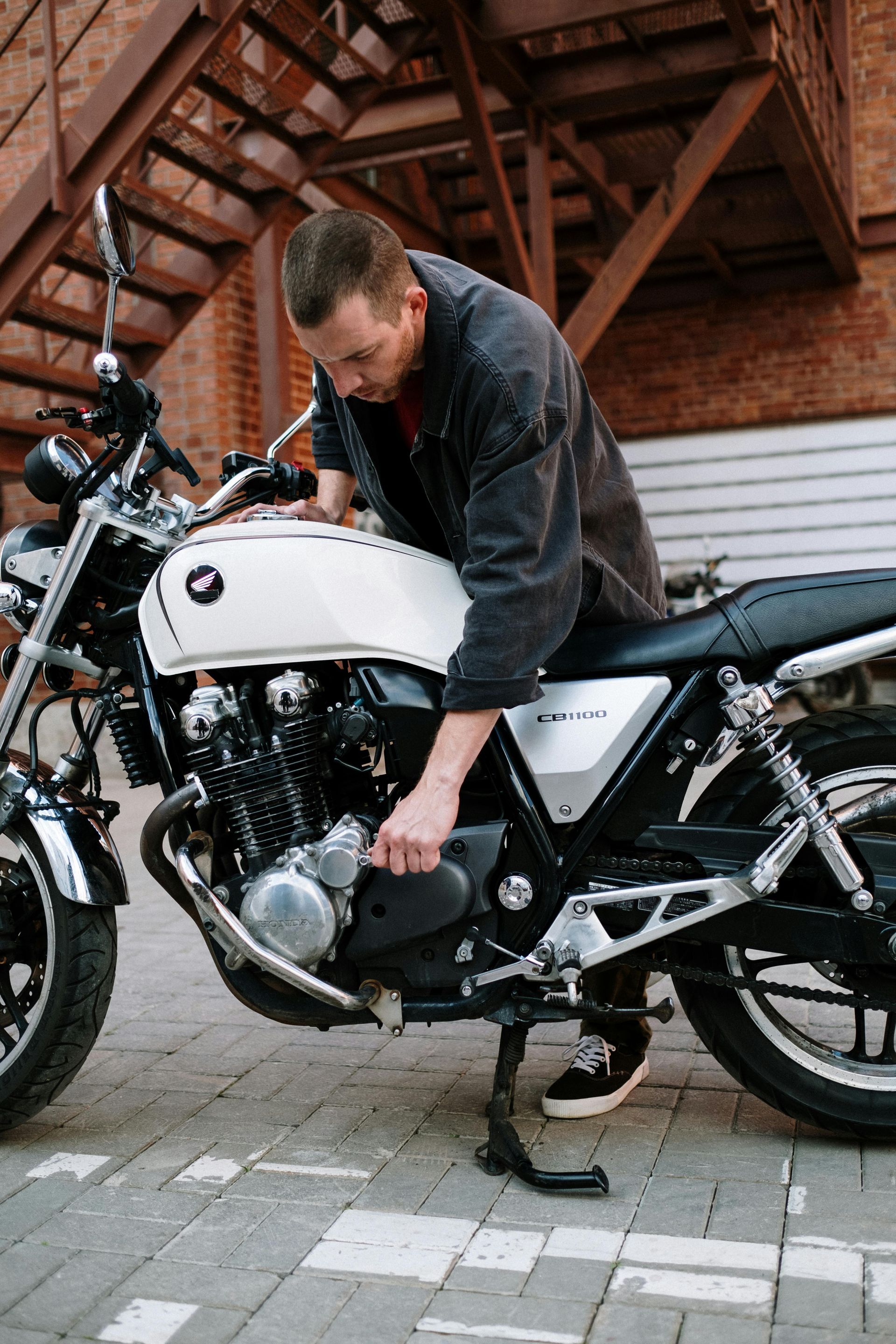 A man working on a motorcycle in a parking lot.