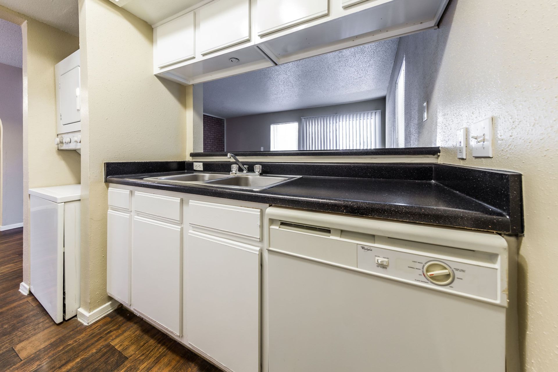 A kitchen with white cabinets, a sink, and a dishwasher at SoCo on the Lake in Austin, TX.