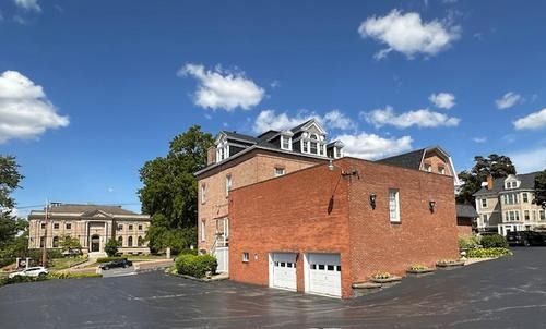 Brick building with garage doors in a paved lot under a blue sky with scattered clouds.