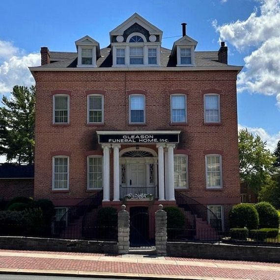 Brick historic building with white trim and central entrance under a blue sky