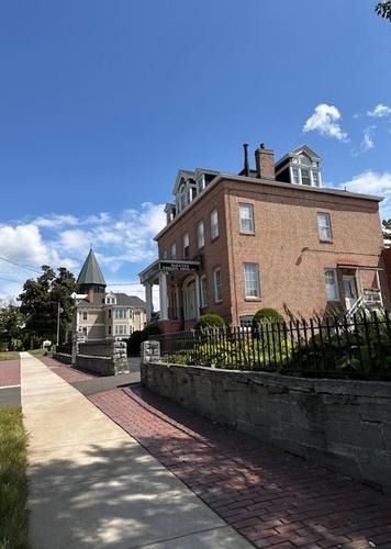 Brick house beside a sidewalk and stone wall under a bright blue sky