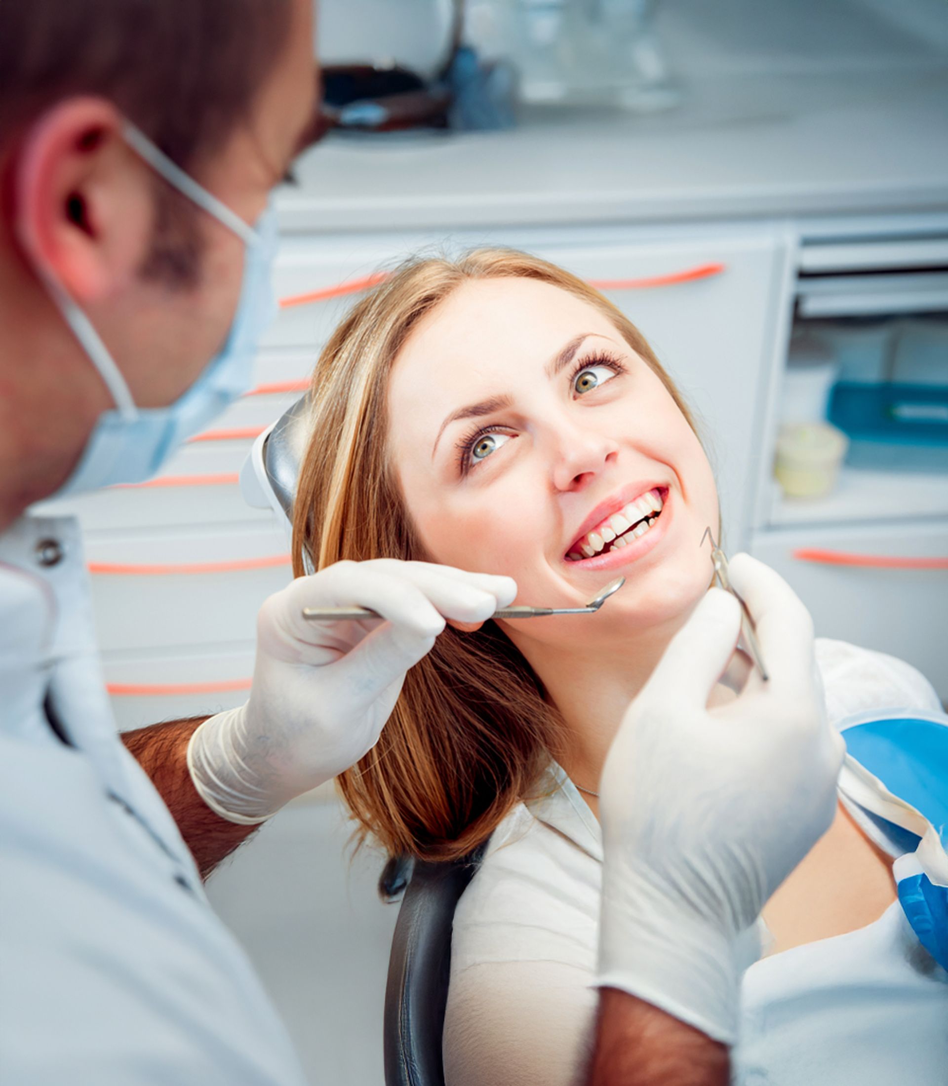 Dentist showing a model of teeth to a patient in a dental office. Both smiling.