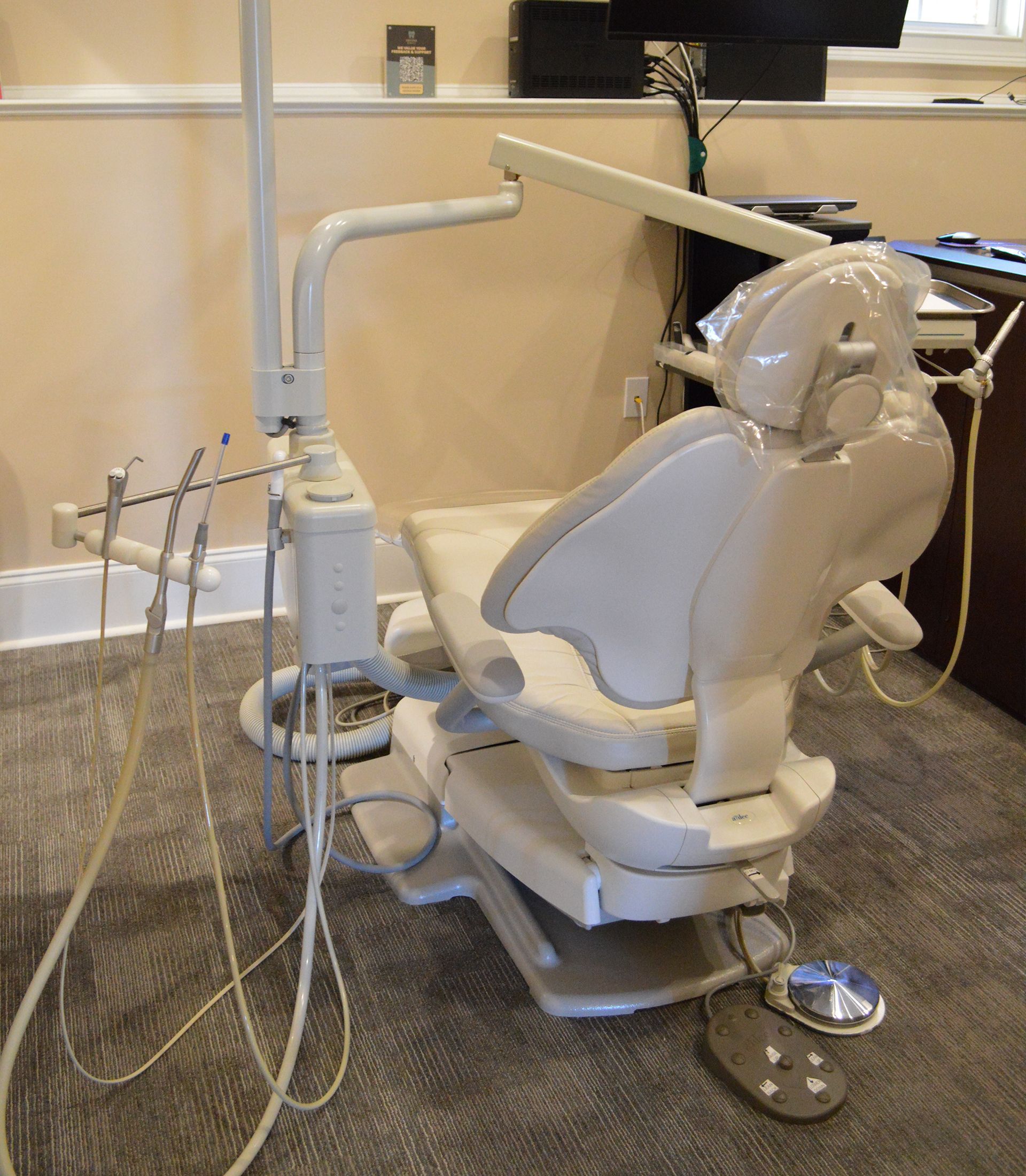 A waiting area with a TV, coffee bar, pink chairs, and a lamp. Neutral color palette,
