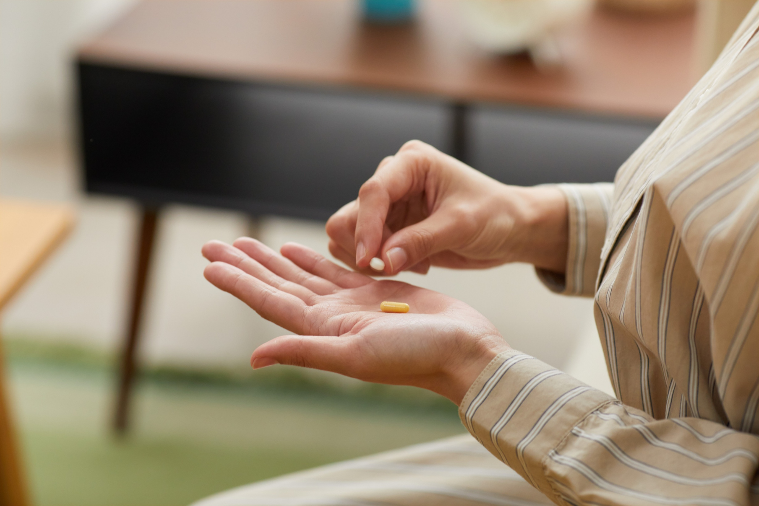 Person holding pills in hand, preparing to take medication.