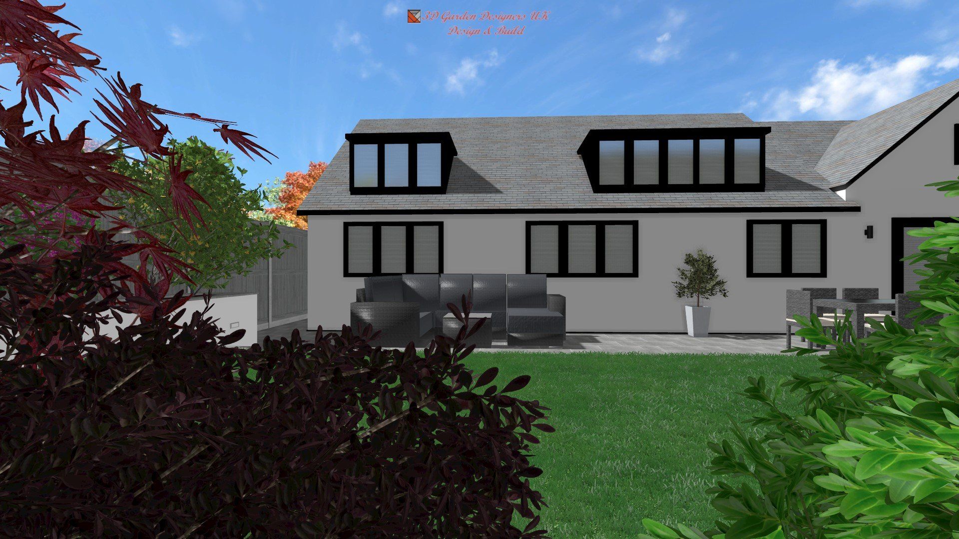 Backyard view of a house with black-framed windows, gray roof, and seating area with foliage in foreground and blue sky.